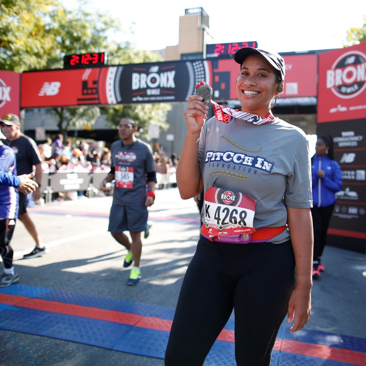 Amber Sabathia holding medal at finish line.