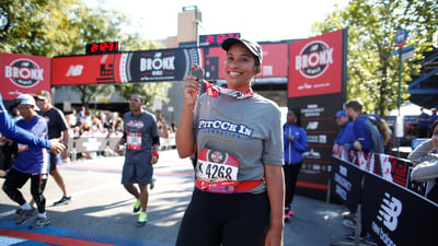Amber Sabathia holding medal at finish line.