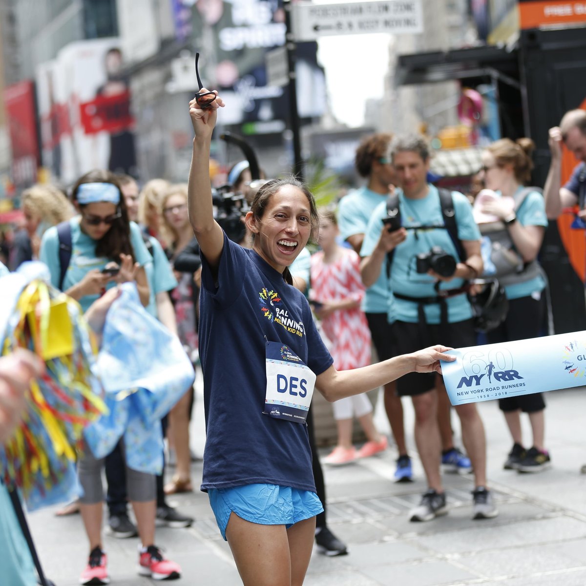 Des Linden holds the tape at a pop-up finish line in Times Square to celebrate Global Running Day.