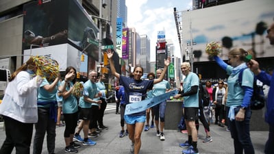 Des Linden breaks the tape at the pop-up finish line in Times Square to celebrate Global Running Day.