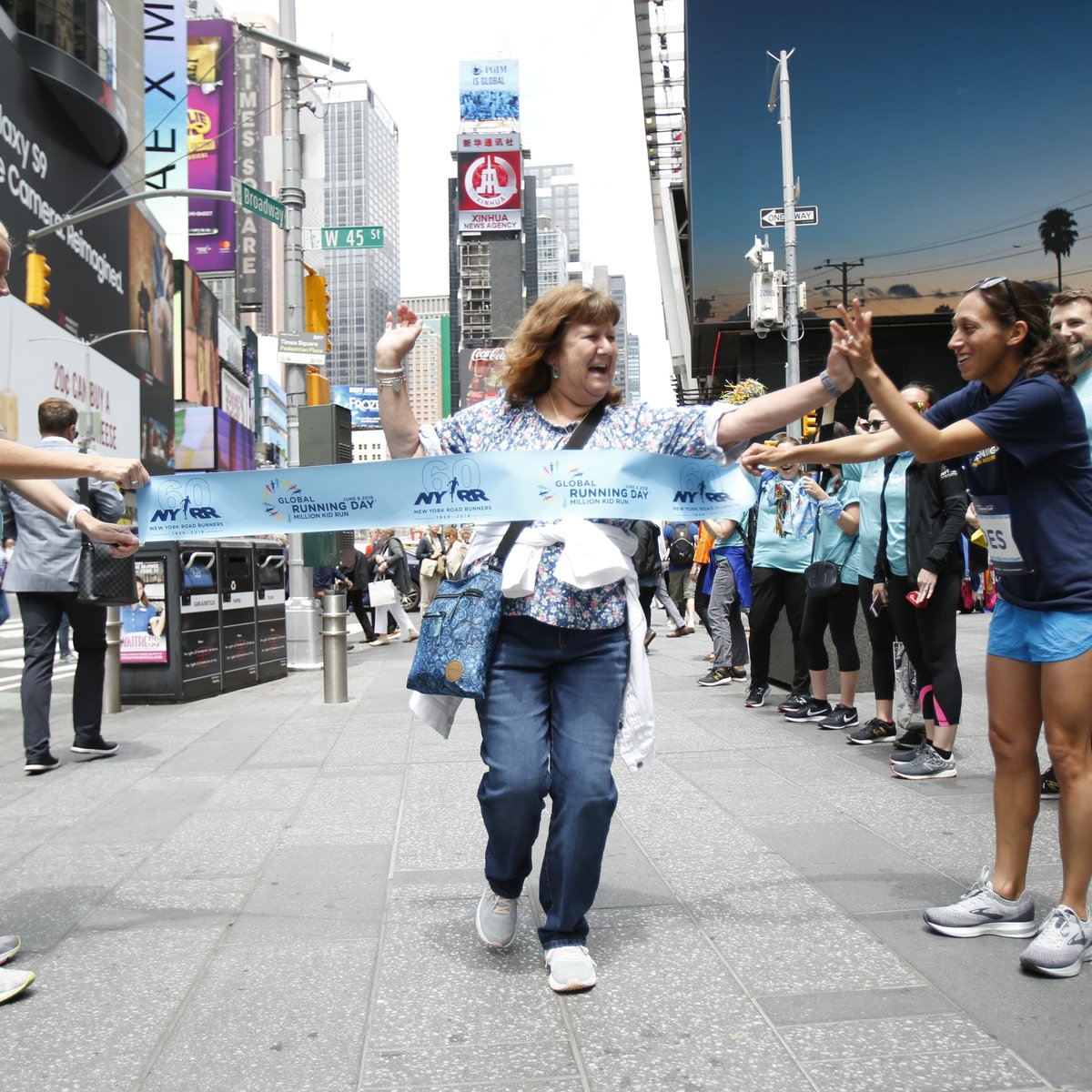 Des Linden (R) high fives a runner crossing the pop-up finish line on Global Running Day in Times Square.