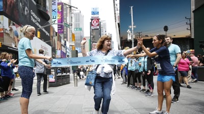 Des Linden (R) high fives a runner crossing the pop-up finish line on Global Running Day in Times Square.