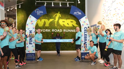 Three-time TCS New York City Marathon champion Mary Keitany breaks a pop-up finish line tape in honor of Global Running Day at the NYRR RUNCenter.