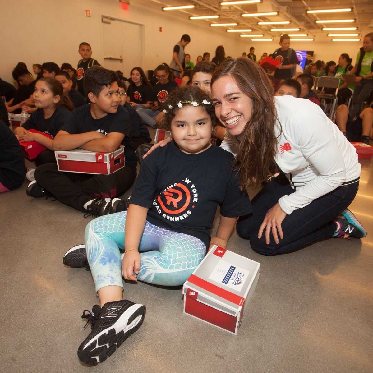 New Balance athlete Abbey D'Agostino distributes shoes on Global Running Day to Rising New York Road Runners as part of the 1 For You 1 For Youth program.