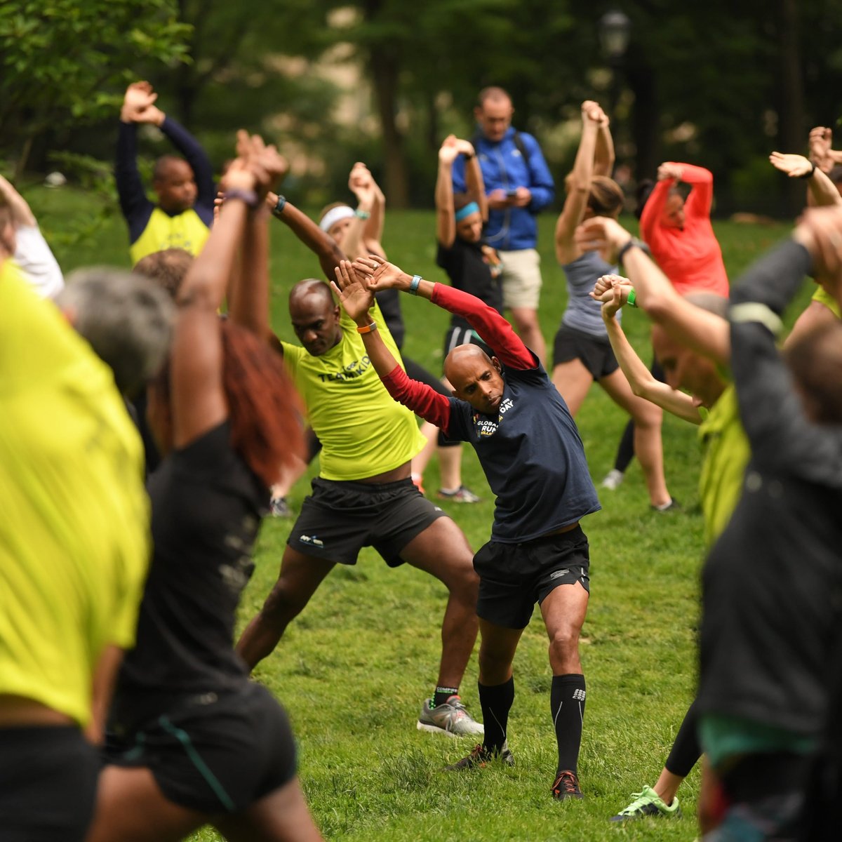 Team for Kids ambassador Meb Keflezighi joins in on a stretching session before heading out on a run through Central Park with Team for Kids runners on Global Running Day.