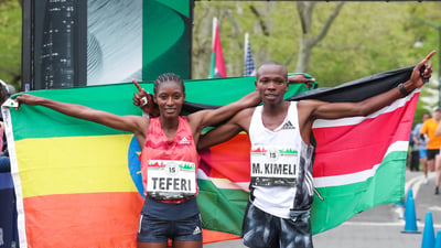 Men's and Women's first place finishers Mathew Kimeli and Senbere Teferi pose with their nations' flags.