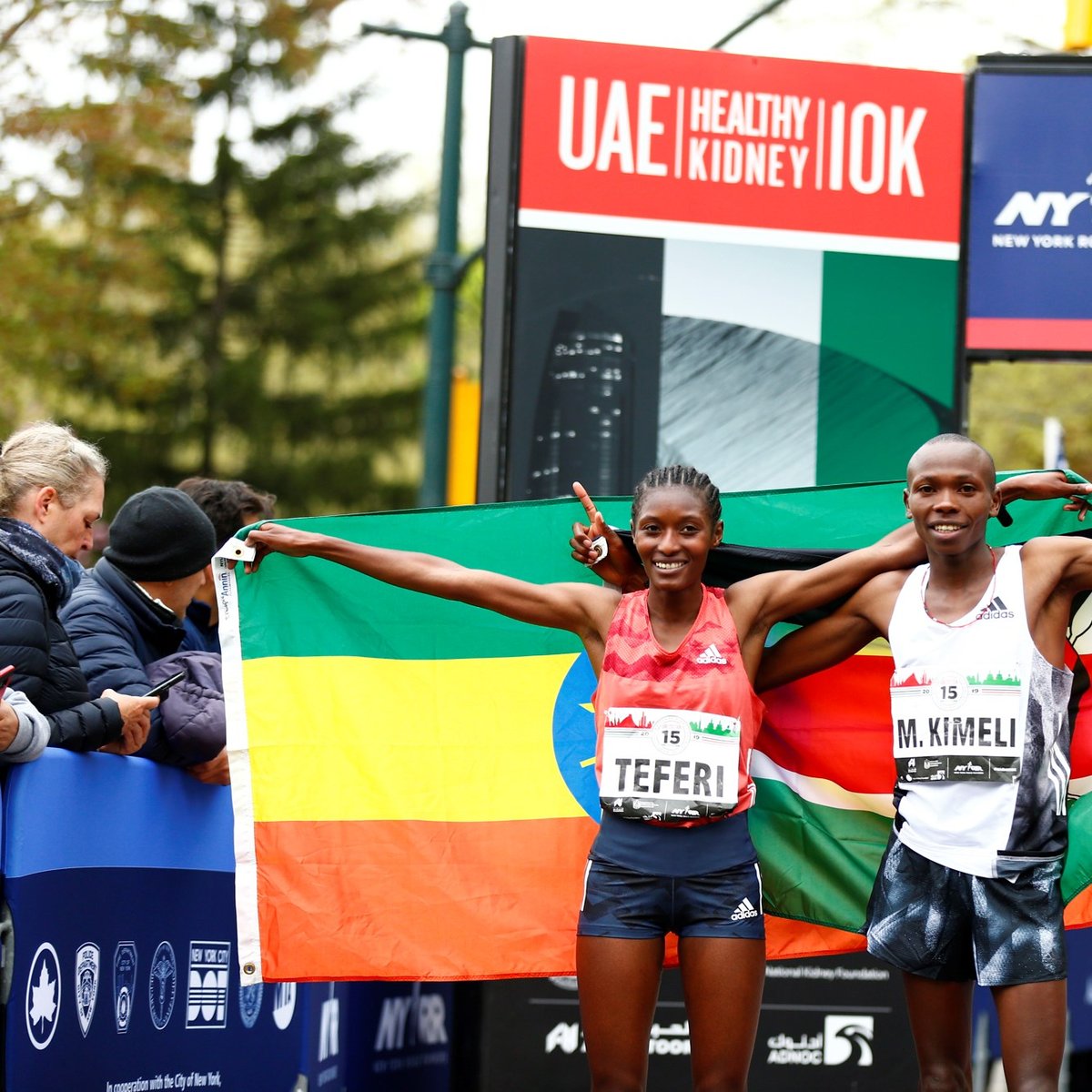 Men's and Women's first place finishers Mathew Kimeli and Senbere Teferi pose with their nations's flags.
