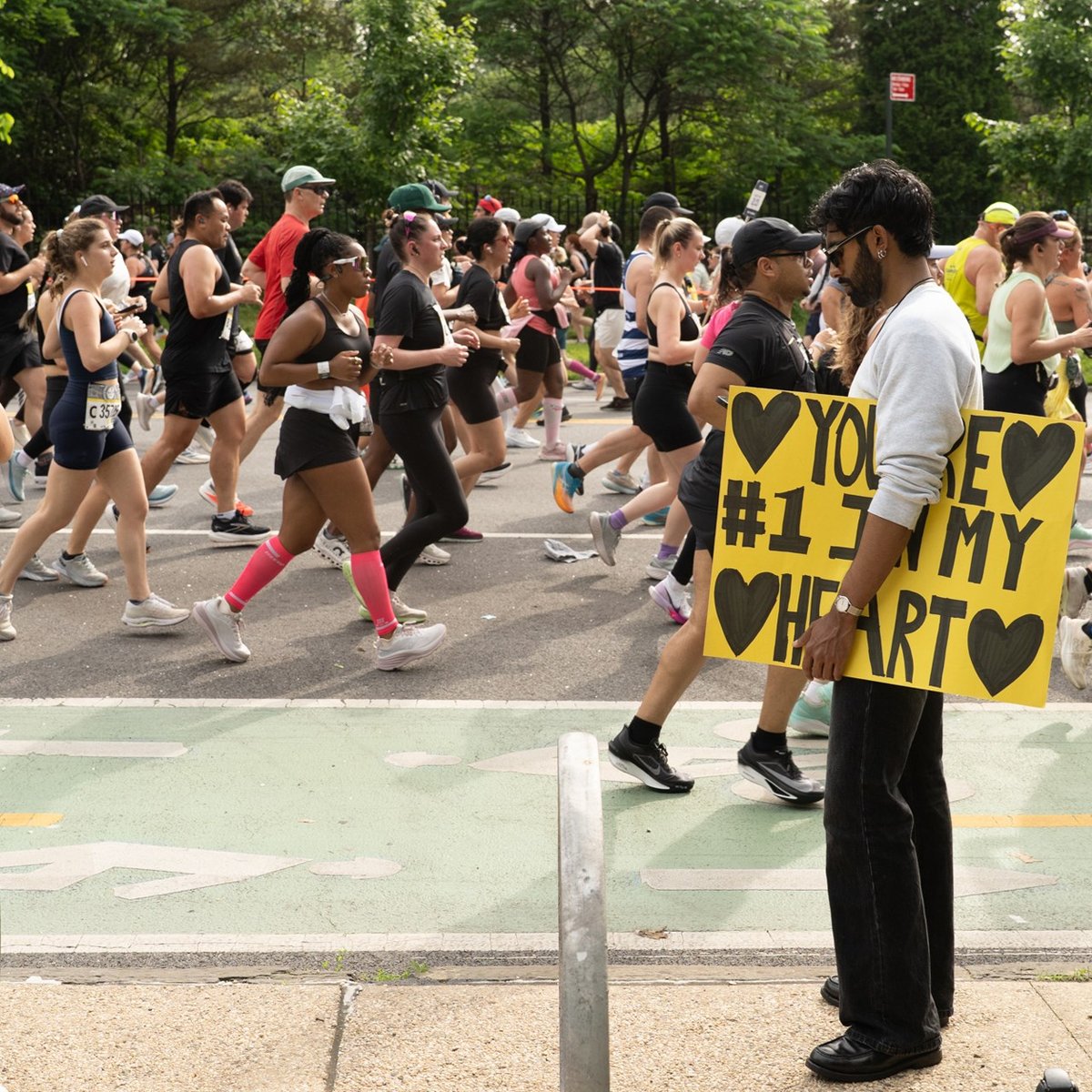 Runners at the RBC Brooklyn Half alongside a spectator with a sign that reads, "You're #1 in my heart"
