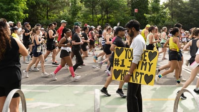 Runners at the RBC Brooklyn Half alongside a spectator with a sign that reads, "You're #1 in my heart"