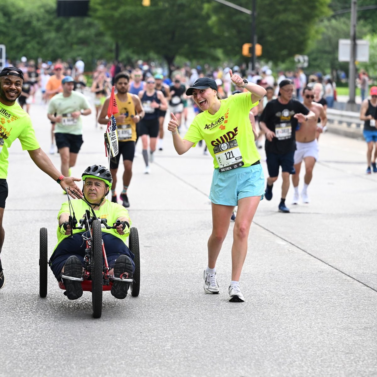 Achilles in a hand cycle with his two guides at the the RBC Brooklyn Half