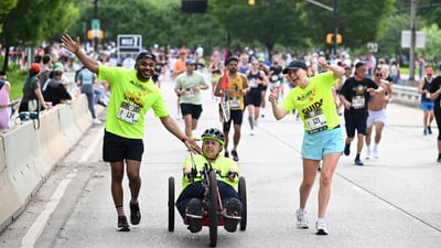 Achilles in a hand cycle with his two guides at the the RBC Brooklyn Half