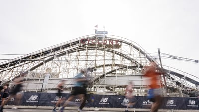 A blurry image of runners running past the Cyclone roller coaster in Coney Island for the RBC Brooklyn Half