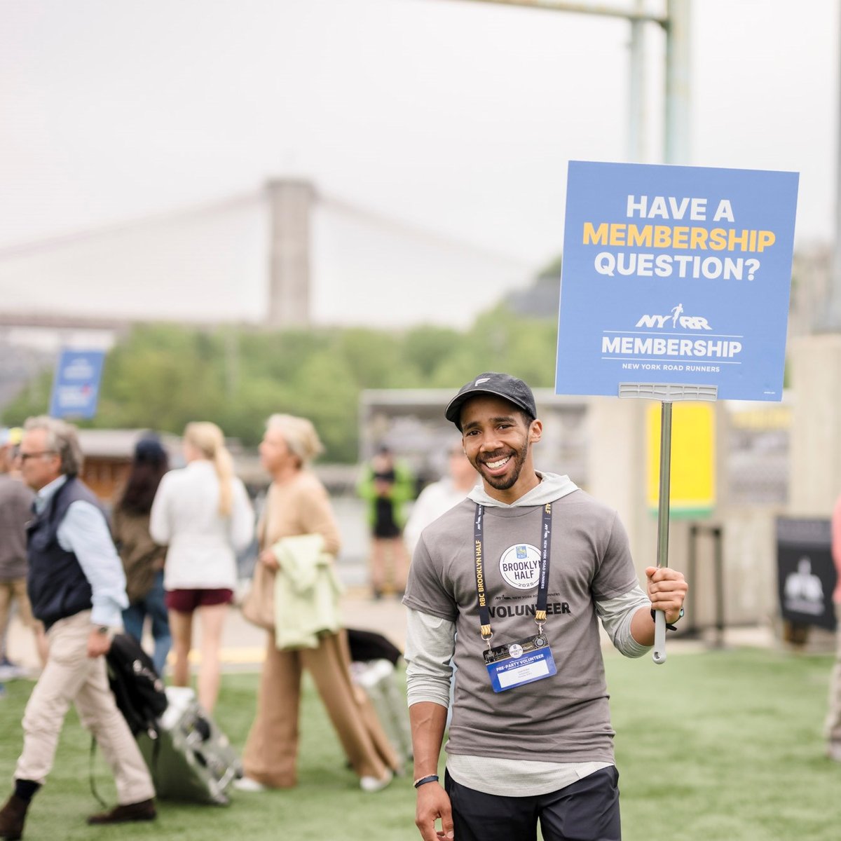 A volunteer at the 2025 RBC Brooklyn Half Pre-Party holding a sign that reads "Have a Membership Question?"