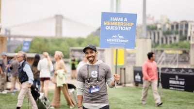 A volunteer at the 2025 RBC Brooklyn Half Pre-Party holding a sign that reads "Have a Membership Question?"
