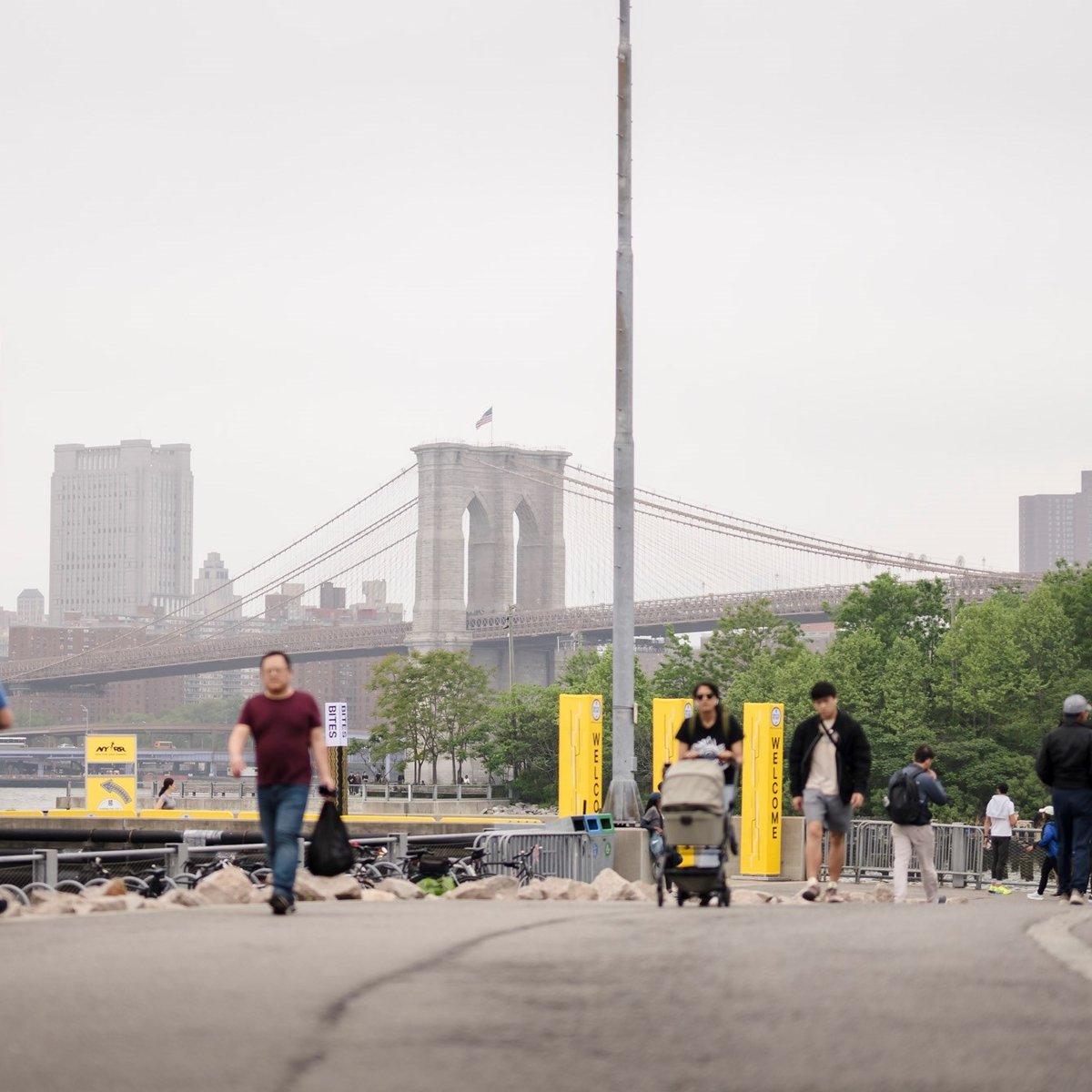 People walking to and from the 2025 RBC Brooklyn Half Pre-Party with the Brooklyn bridge in the background