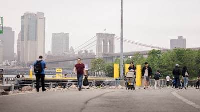 People walking to and from the 2025 RBC Brooklyn Half Pre-Party with the Brooklyn bridge in the background