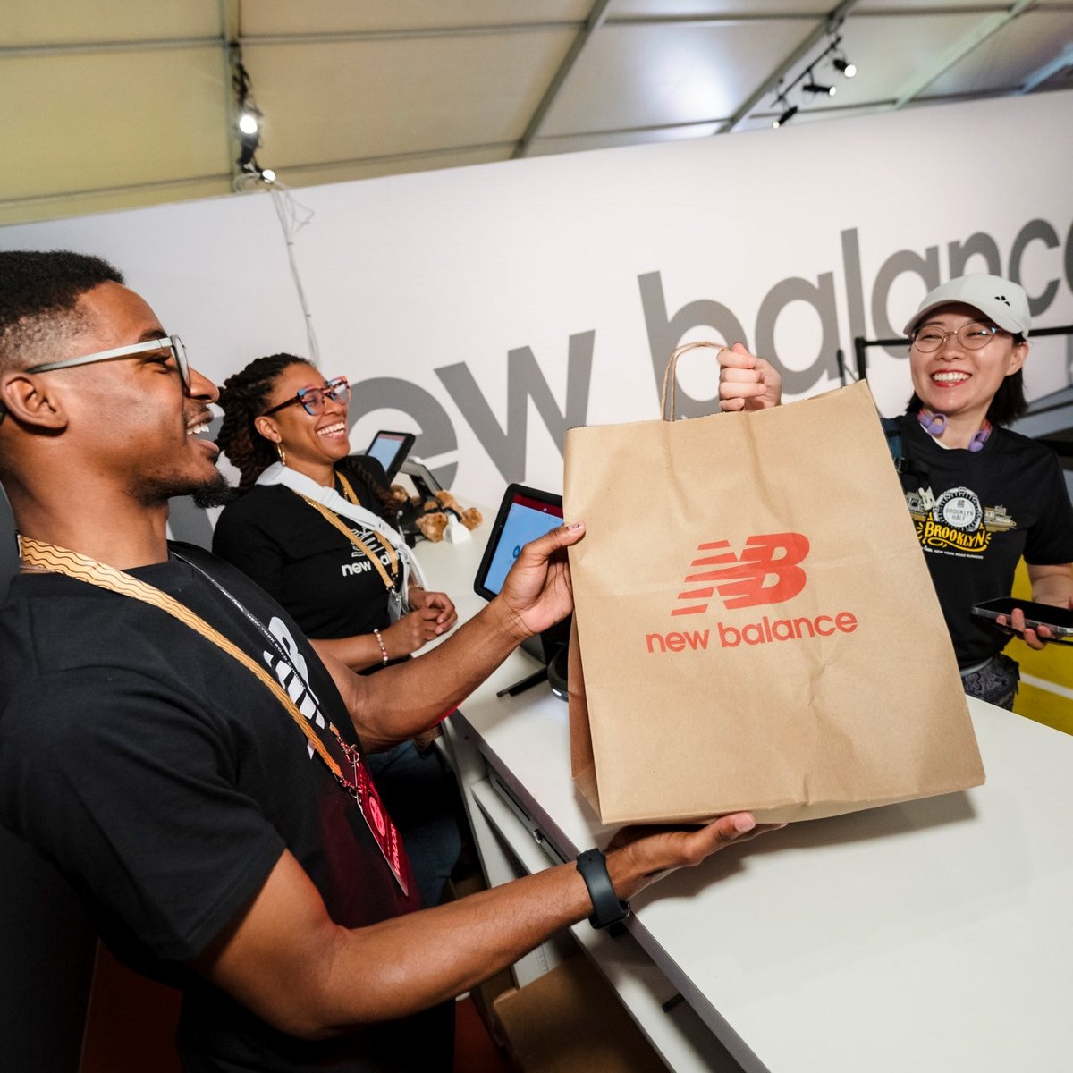 A woman is being handed a New Balance shopping bag at the New Balance store at the 2025 RBC Brooklyn Half Pre-Party