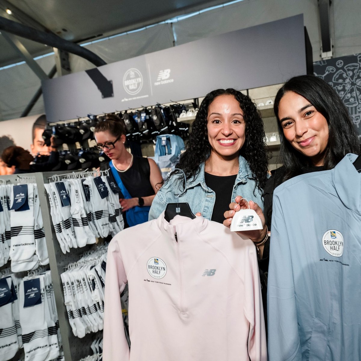 Two women pose for a photo with New Balance clothes in the New Balance store at the 2025 RBC Brooklyn Half Pre-Party