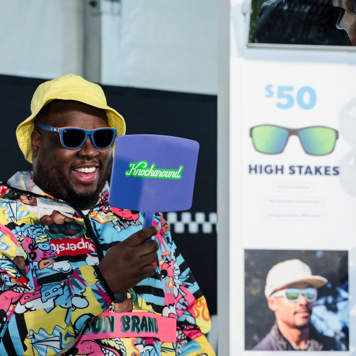 A man looks in the mirror as he tries on Knockaround sunglasses at the 2025 RBC Brooklyn Half Pre-Party