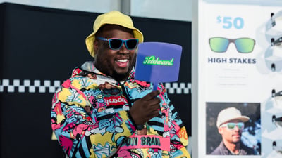 A man looks in the mirror as he tries on Knockaround sunglasses at the 2025 RBC Brooklyn Half Pre-Party