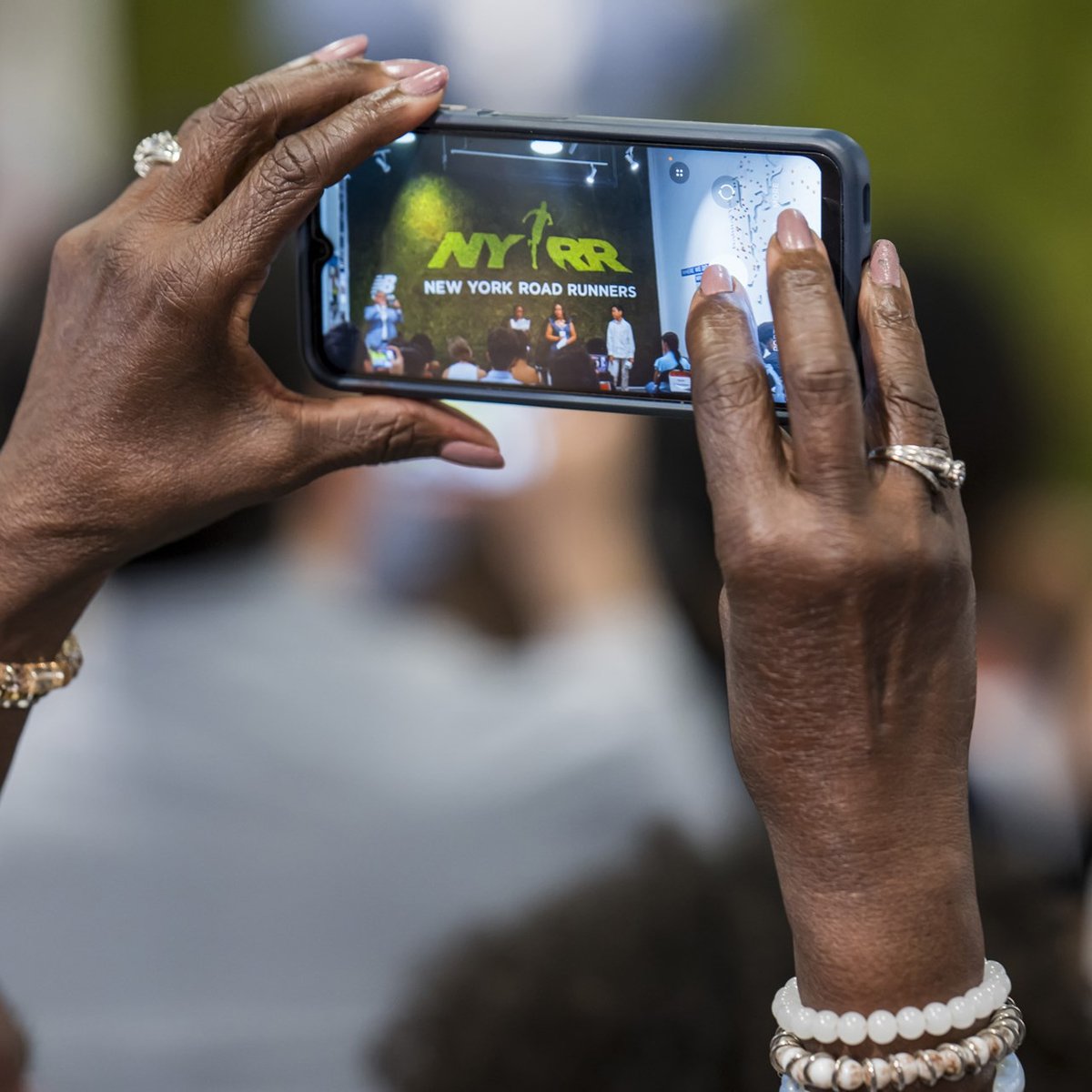 Someone taking a picture on their phone of the Youth Ambassador graduation ceremony at the NYRR RUNCenter