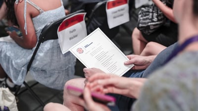 Someone holding and looking at the program for the youth ambassador graduation