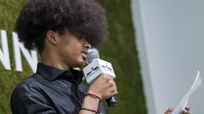 A youth ambassador speaks into a mic at graduation