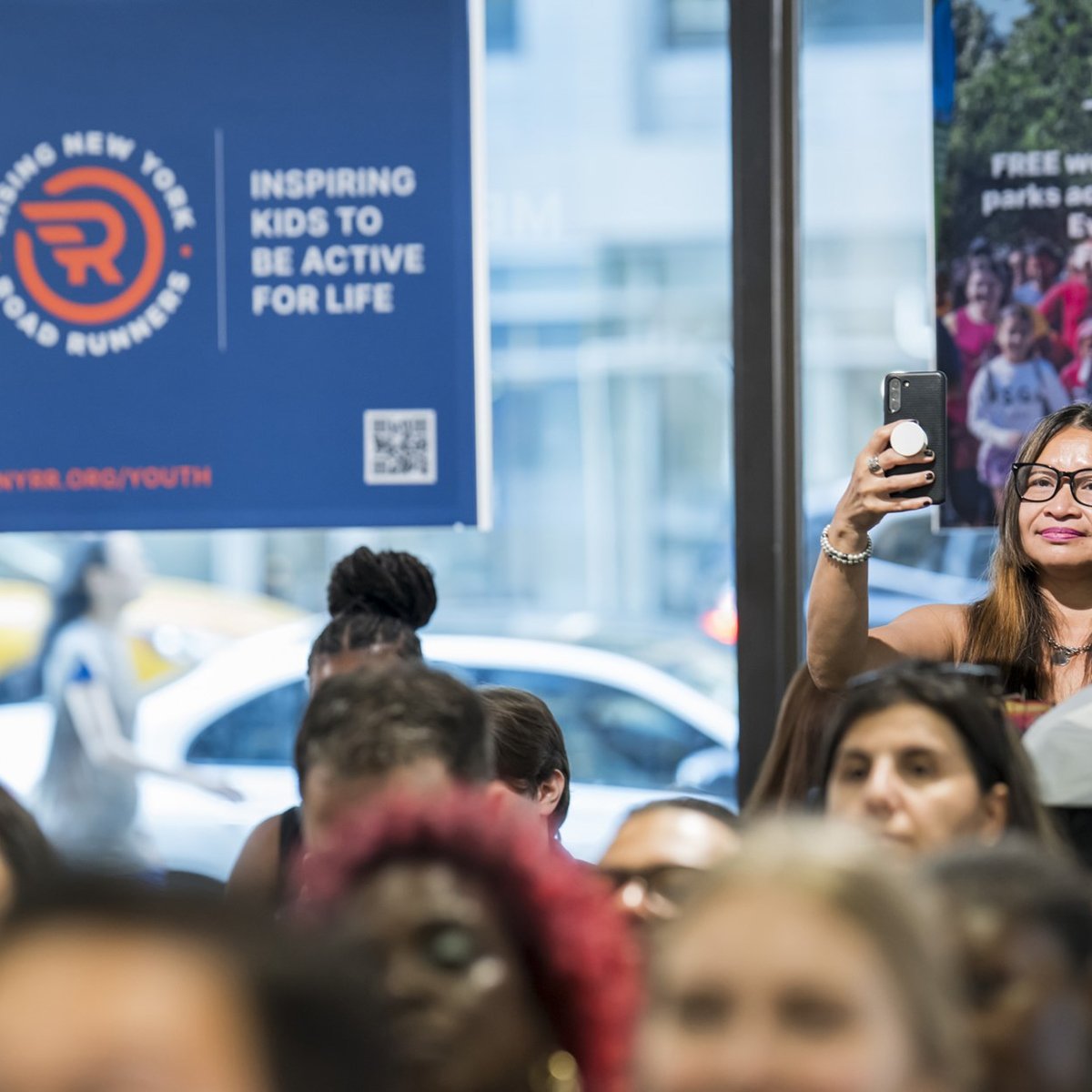 People in the audience take pictures on their phones at the youth ambassador graduation