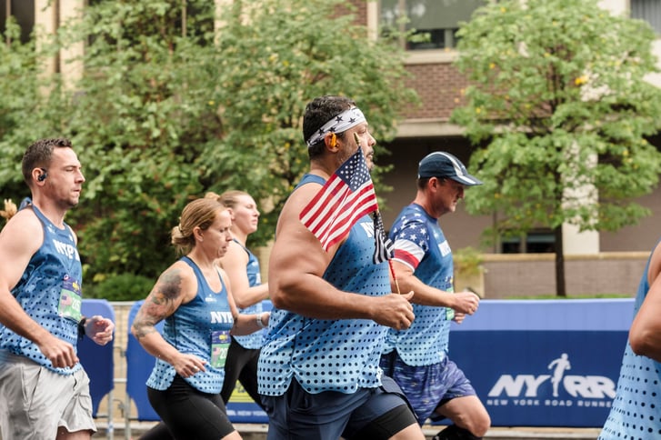 NYPD runner holding a flag on the New Balance 5th Avenue Mile course