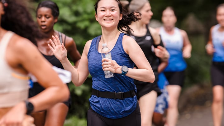 Young woman runner with others in background at summer 2025 NYRR Unlock Group Training session