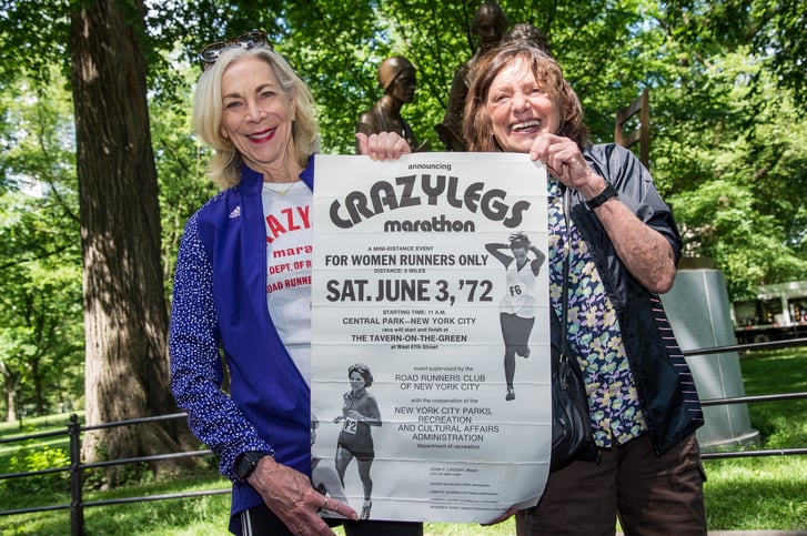 Nina Kuscsik and Kathrine Switzer with Crazylegs Mini Marathon 1972 poster in Central Park at media event in 2022.