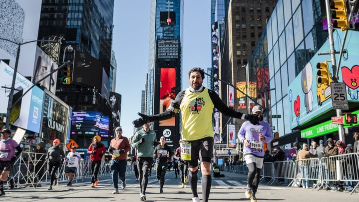 Runner in Times Square holds his arms out during race