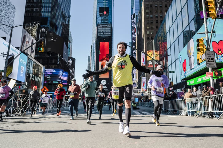 Runner in Times Square holds his arms out during race