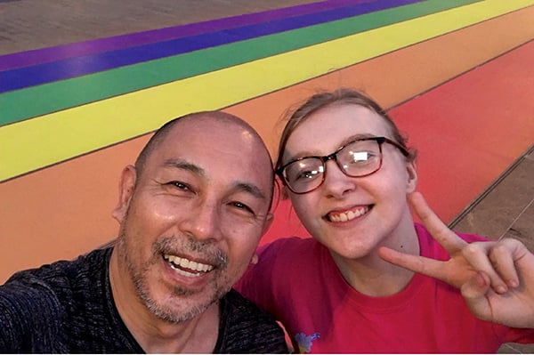 Father and daughter with Pride rainbow backdrop