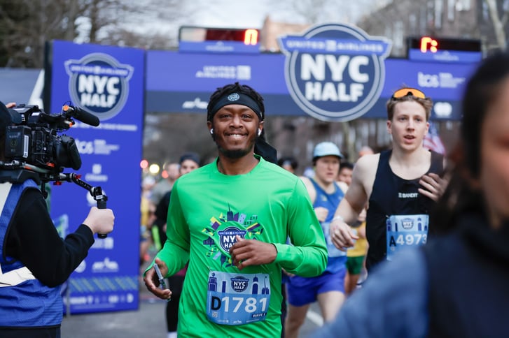 Runner smiles after crossing the NYC Half finish line