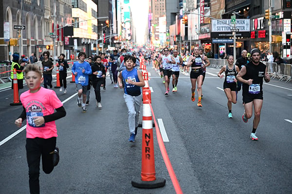 Youth and adult runners in Times Square at 2022 UA NYC Half