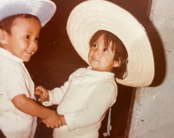 Keila Merino as a child dancing with cousin wearing hats
