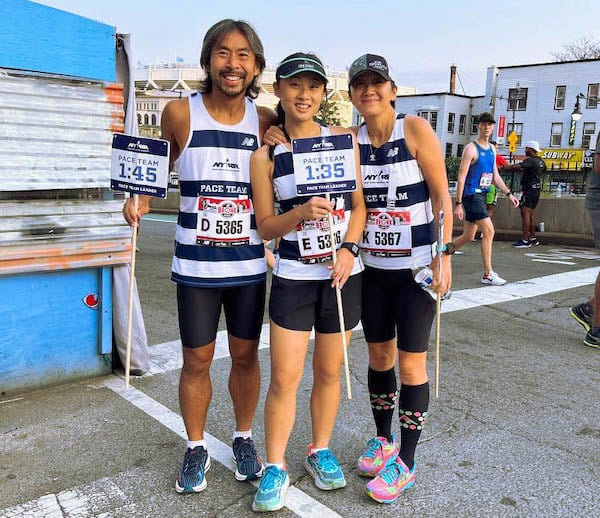NYRR Pace Team members the Otto, Louisa, and Olivia Lam stand together in pace uniforms.