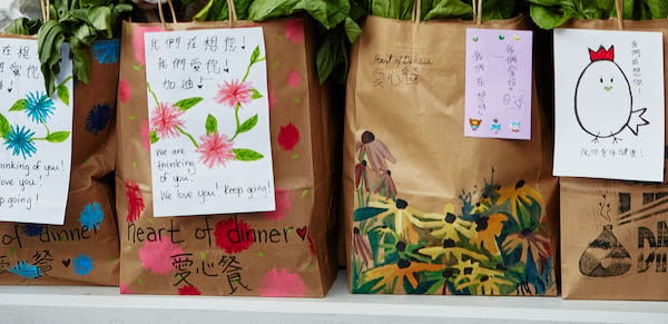Colorfully decorated paper bags for Heart of Dinner care packages.