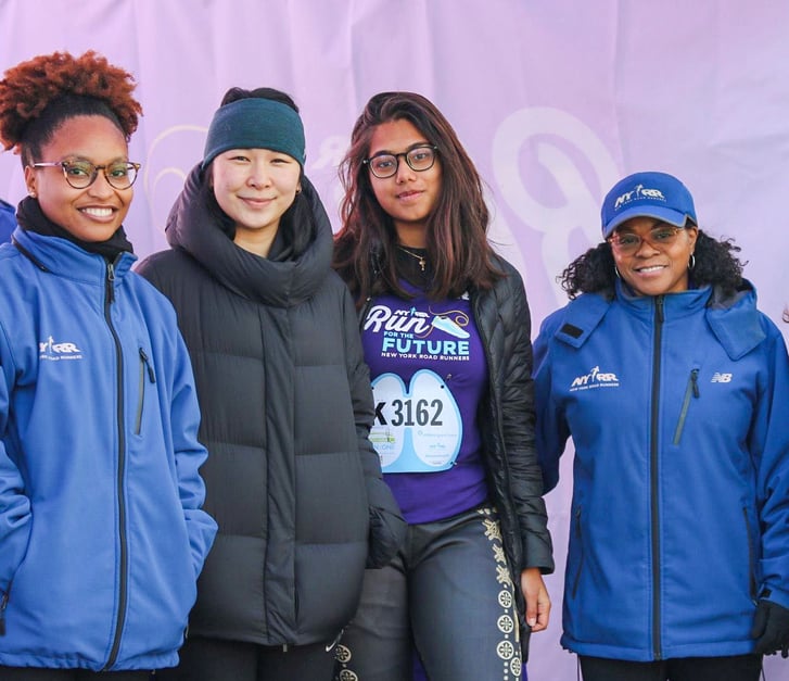 Two Run for the Future alumnae with NYRR staff in a tent before a race