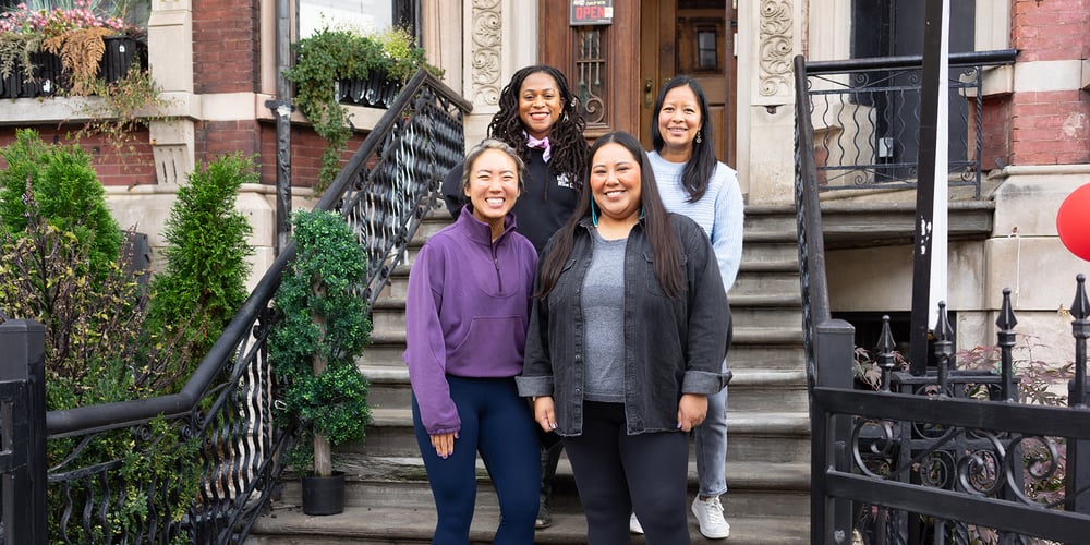 NYRR Contributors Circle members standing on steps at Harlem Run House November 2023
