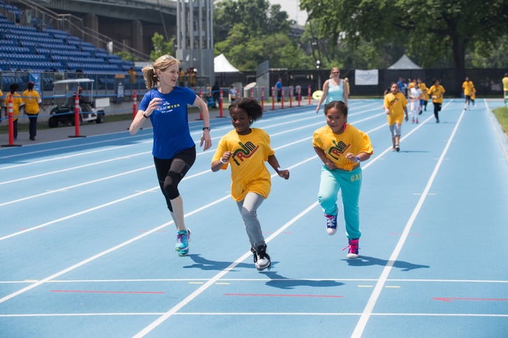 Mary Wittenberg runs with students at a National Running Day celebration at Icahn Stadium.