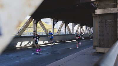 Runners running under bridge