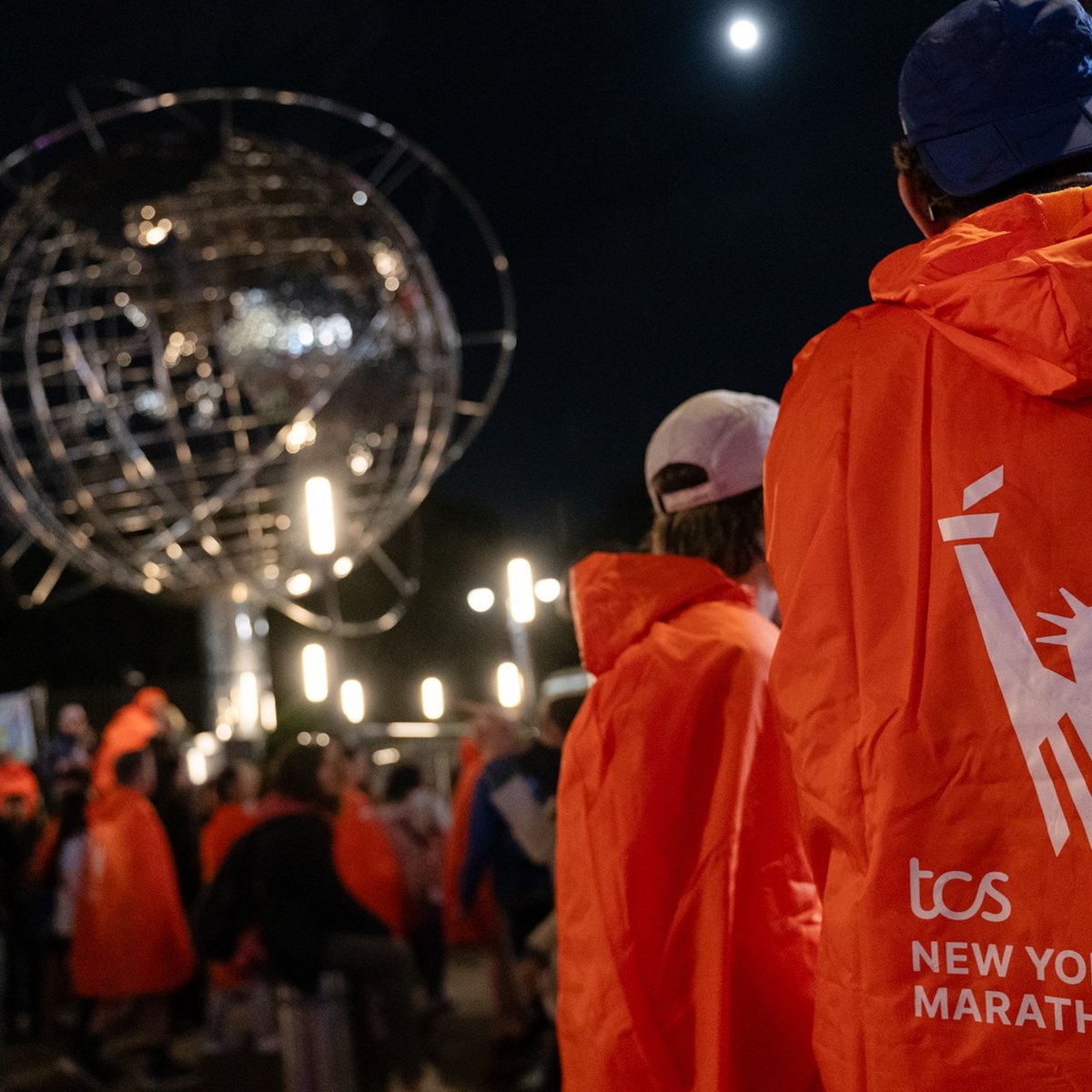 Marathon finishers in their matching ponchos with the backdrop of the globe in Columbus Circle