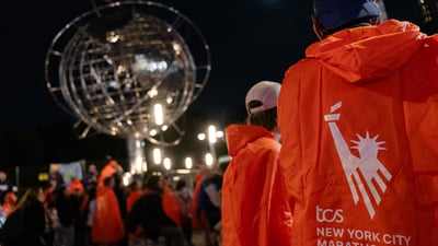 Marathon finishers in their matching ponchos with the backdrop of the globe in Columbus Circle
