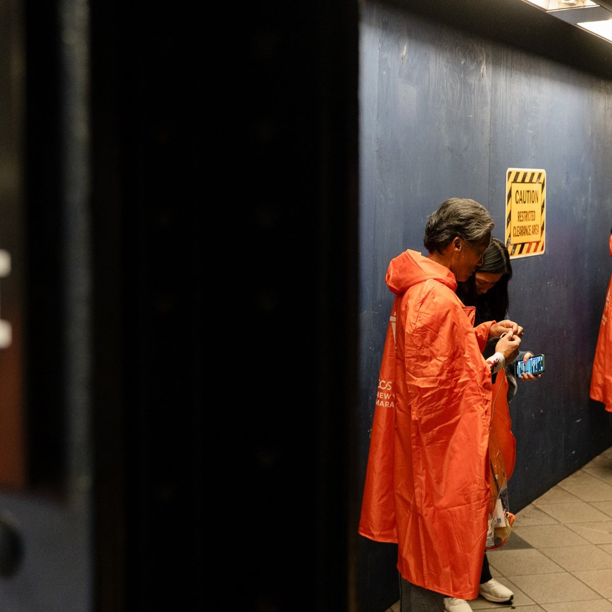 Marathon finishers in their matching ponchos by the 59th St subway station