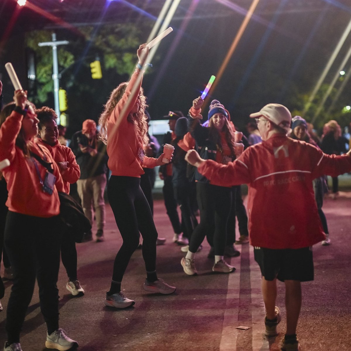 Staff members celebrating final finishers with glow sticks in the air