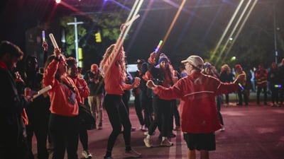 Staff members celebrating final finishers with glow sticks in the air