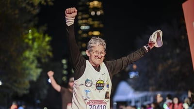 A final finisher crosses the finish line with his arms outstretched overhead