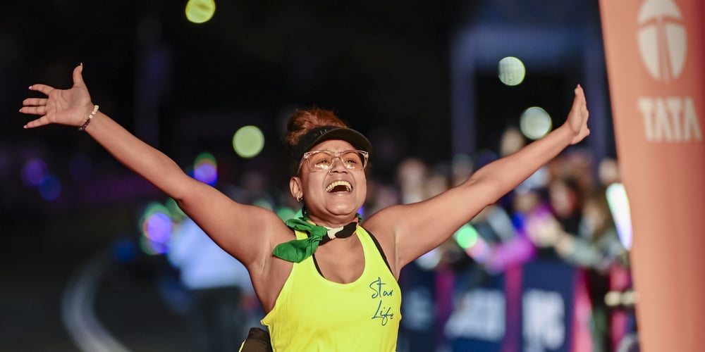 A final finisher crosses the finish line with her arms outstretched